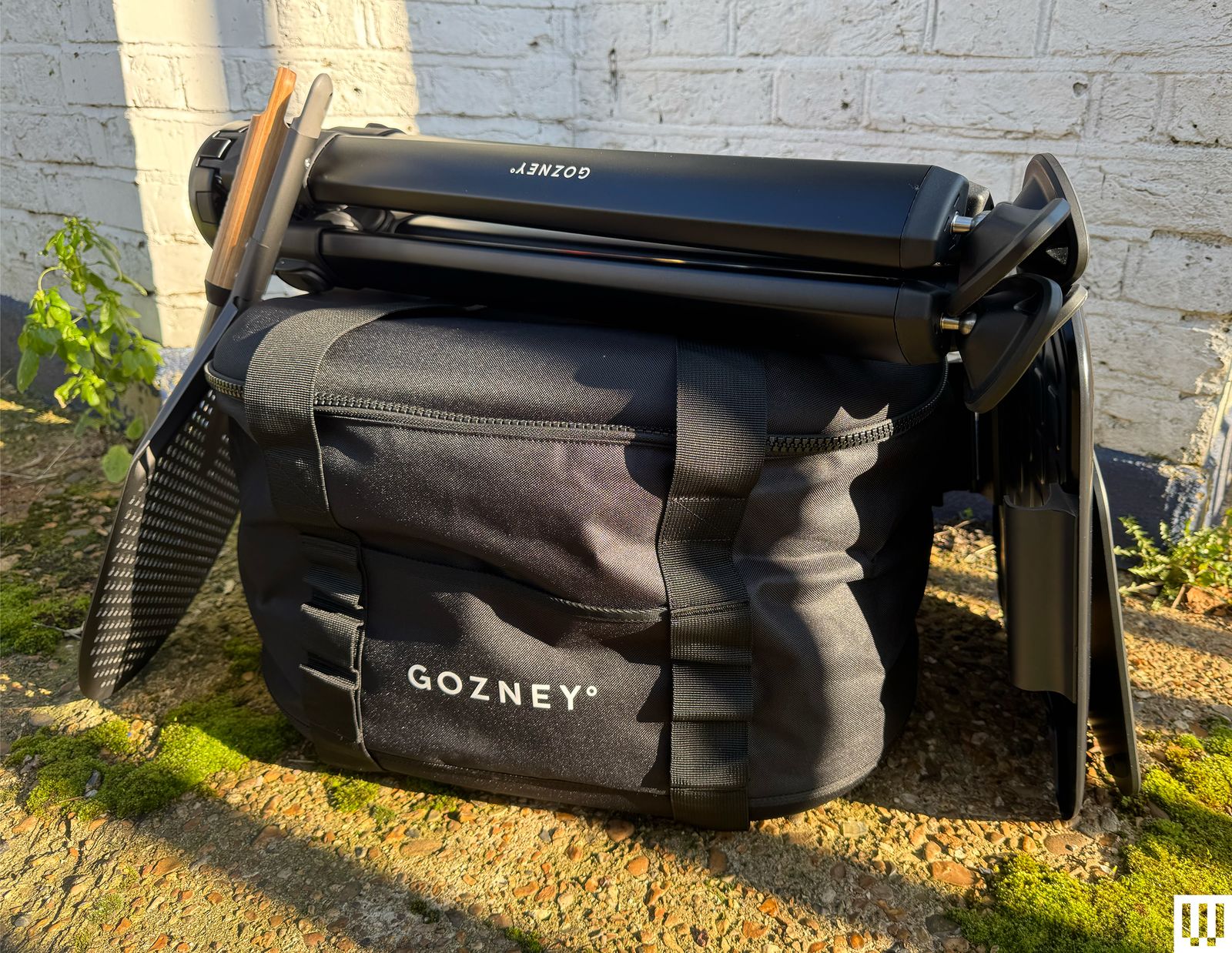 Front view of Gozney Tread Pizza Oven packed in a black bag with the stand folded up on top.