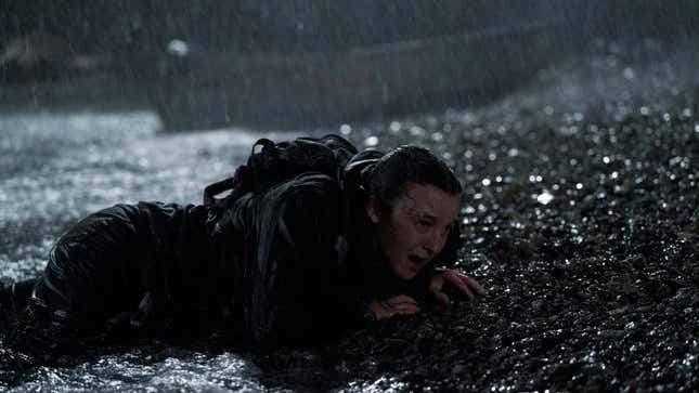 Ellie crawls on a beach as rain pours down.